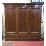An Edwardian mahogany triple wardrobe, three panelled door enclosing a partially fitted interior,