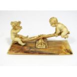 19th century ivory carving - two naked children seated on a rustic see saw, 14cm long