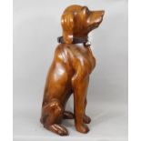 A carved hardwood figure of a seated hound, 61cm high