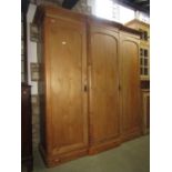 A Victorian stripped pine shallow breakfront wardrobe with moulded cornice over three arched