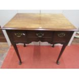 A Georgian mahogany lowboy fitted with three drawers over a central frieze raised on four pad