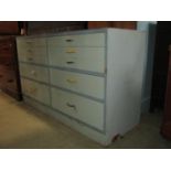 A low painted wooden chest fitted with an arrangement of ten drawers raised on a slightly recessed