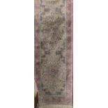 Cashmere type runner decorated with various floral medallions upon a pink ground, 300 x 80cm