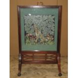 An Edwardian mahogany firescreen with moulded frame, swept supports and pierced fretwork detail,