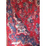 Persian rug with floral spray decoration in blue upon a red ground, 260 x 160cm