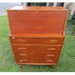 A mid 20th century teak writing bureau, the fall flap over four long drawers raised on tapered