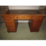 A Victorian medium to light oak kneehole twin pedestal writing desk with inset worn leather panelled