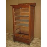 An early 20th century oak floorstanding filing cabinet enclosed by a rise and fall tambour door