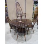 An Ercol dark stained elm and beechwood oval drop leaf kitchen table raised on splayed square