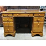 A modern pine kneehole twin pedestal desk with inset leather writing surface over an arrangement