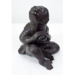 A heavy bronzed figure of a seated monkey, with genial face, clasping a fruit, 16cm high