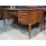 A medium to light oak knee-hole desk in the Louis XV style with moulded outline over an