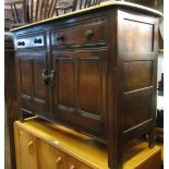 An Ercol dark stained elm cottage dresser base with stripped top over two frieze drawers and