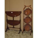 An unusual mahogany two tier oval drop leaf occasional table raised on turned and swept supports