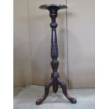 An Edwardian mahogany torchere raised on a turned and carved pillar with swept tripod