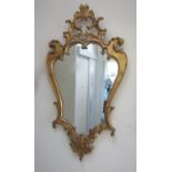 A contemporary reproduction Rococo style shield shaped wall mirror with scrolling acanthus detail