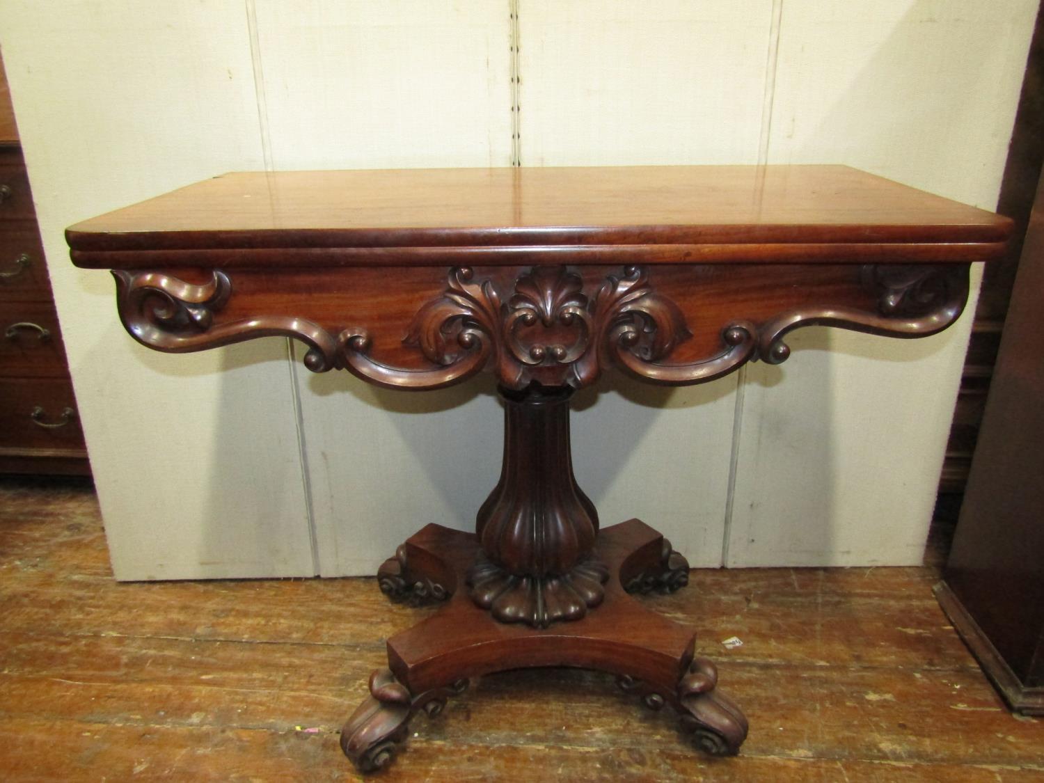 A Regency mahogany fold over top tea table, raised on a vase shaped pillar and platform base, with