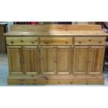 A contemporary stripped pine kitchen dresser base fitted with three frieze drawers over four