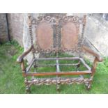 A Carolean style walnut two seat settle of usual form, with barley twist supports, carved and
