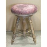 A beechwood piano/music stool with circular revolving dry maroon leather upholstered seat, raised on