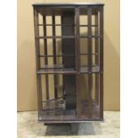 An Edwardian dark stained floorstanding revolving bookcase of square cut form with open segmented