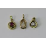 Three gold pendants comprising a 14ct ruby example, a further 14ct diamond example and an