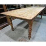 A stripped pine farmhouse kitchen table, the rectangular planked top with cleated ends raised on