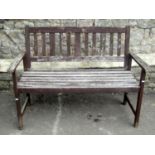 A contemporary but weathered stained teak two seat garden bench with slatted seat and back, 120 cm