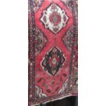 A full pile Persian carpet with floral panels upon a washed red ground, 280 x 90cm