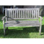 A weathered contemporary teak two seat garden bench with slatted seat and slightly curved slatted