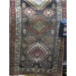 Antique Afghan runner with central medallions upon a dark ground with red fielded borders, 300 x