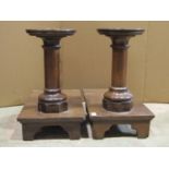 A pair of low oak ecclesiastical stands with turned columns raised on platforms with bracket feet