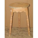 A small stripped pine cricket table with circular top raised on splayed partially ring turned and