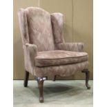 A Georgian style wing armchair with shaped outline, generous wide seat, upholstered finish and loose