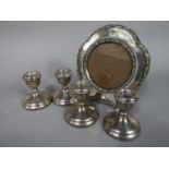 Set of four silver dwarf candlesticks, together with a further silver easel frame with scrolled