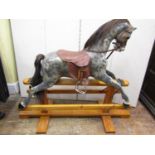 A traditional rocking horse with composite body and painted dapple grey finish, raised on a pine