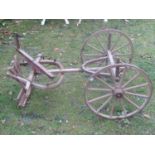 A small vintage wooden hand cart chassis with spoke wheels and iron rims