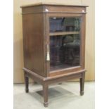 An Edwardian walnut side cabinet, freestanding and enclosed by a rectangular glazed panelled door,