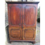 A Georgian mahogany dwarf robe enclosed by a pair of moulded panelled doors beneath a dentil cornice