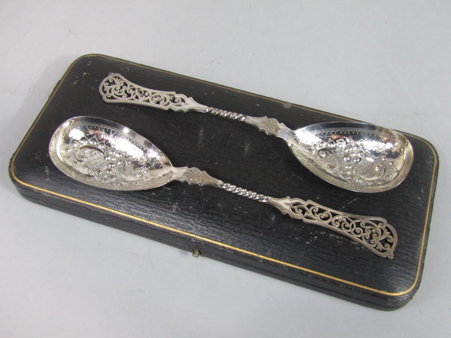 Good quality pair of fancy silver serving spoons with relief floral bowls and pierced scrolled