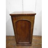 A Victorian mahogany cabinet enclosed by an arched and panelled door, the interior fitted with