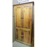 A stripped pine kitchen cupboard, freestanding and enclosed by two pairs of rectangular panelled