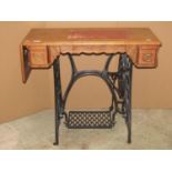 A Singer cast iron treadle sewing machine base and original drop leaf top incorporating three