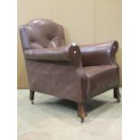 An early 20th century easy chair in the traditional style with rolled arms and shaped back, faux