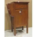 A small oak freestanding side cupboard with fall front beneath a hinged box compartment and magazine