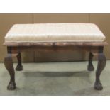 A hardwood stool of rectangular form with upholstered seat, serpentine moulded outline and claw