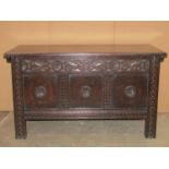 An old English style dark stained oak coffer with hinged lid and panelled frame, the front elevation