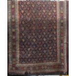 An old Persian rug with geometric paisley design upon a dark ground, 250 x 125cm