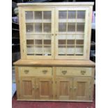 A stripped pine farmhouse kitchen dresser, the base enclosed by four rectangular panelled doors