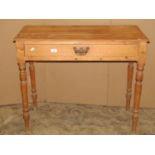 A stripped pine side table fitted with a shallow frieze drawer raised on turned supports together